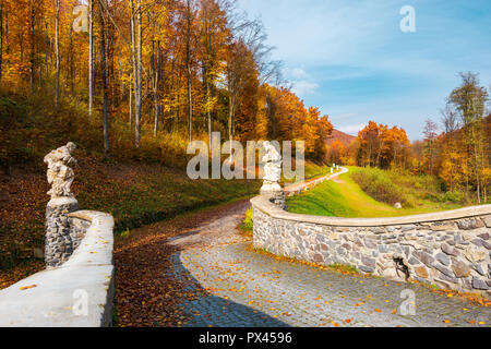 Weg von der Steinernen Brücke in den Wald Bäume im Herbst Farben. blauer Himmel über der Landschaft Stockfoto