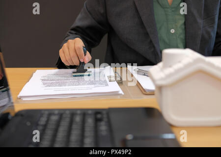 Real estate agent mit stamper Für das Stempeln auf Hypotheken darlehen Vertrag genehmigte Dokument Stockfoto