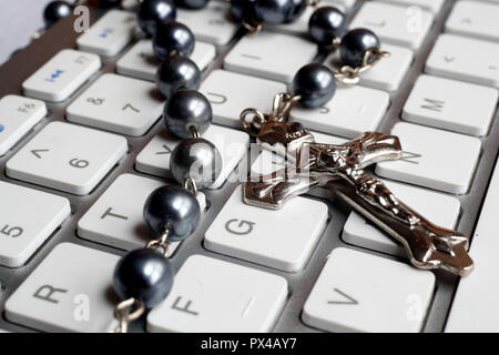 Christian Rosenkranz auf eine weiße Tastatur. Stockfoto