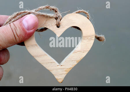 Mann hält eine hölzerne Herz. Close-up. Stockfoto