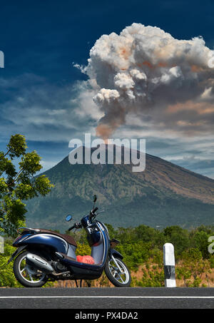 29 Juni 2018, Bali, Indonesien Scooter am Rande der ruad mit Mount Agung Vulkan dramatischen Ausbruch im Hintergrund stehen. Massive Wolken als Stockfoto