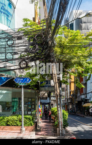Ausstehende Strommast mit reichlich chaotisch Strom Kabel und Leitungen in einer Straße von Bangkok, Thailand. Stockfoto