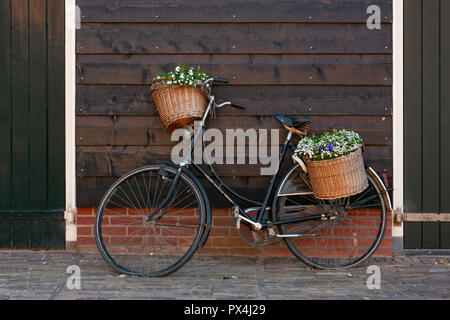 Alt-niederländischen Fahrrad mit blumenkörben gegen eine hölzerne Wand lehnt Stockfoto