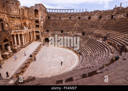 Bosra, Syrien: Besucher auf den Ruinen des zweiten Jahrhunderts AD römische Theater von Bosra später komplett durch ein Ayyūbid mittelalterliche Festung eingeschlossen. Mit Sitz Stockfoto