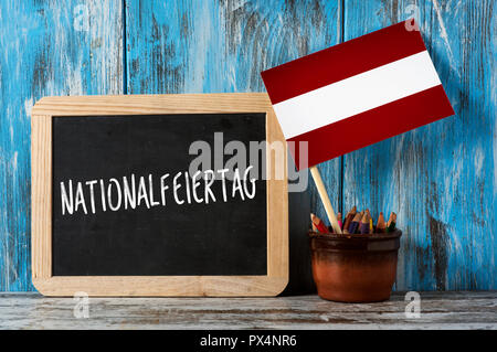 Ein fachwerkhotel Schiefertafel mit dem Text Nationalfeiertag, dem Nationalen Tag der Österreich auf Deutsch geschrieben, und eine Österreichische Fahne auf einem rustikalen Holzmöbeln surf Stockfoto