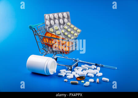 Warenkorb voller Drogen und Medikamente Pillen auf blauem Hintergrund Stockfoto
