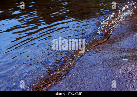 Nassen Sand und kleine Welle am Sandstrand. Nahaufnahme Bild horizontal. Stockfoto