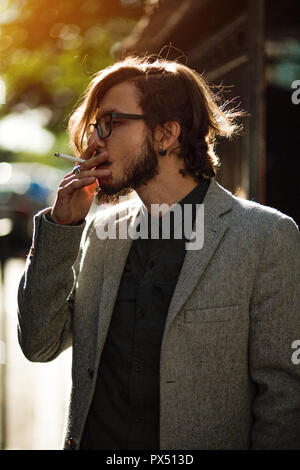 Ein Mann mit langen Haaren raucht außerhalb Stockfoto