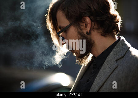 Ein Mann mit langen Haaren raucht außerhalb Stockfoto