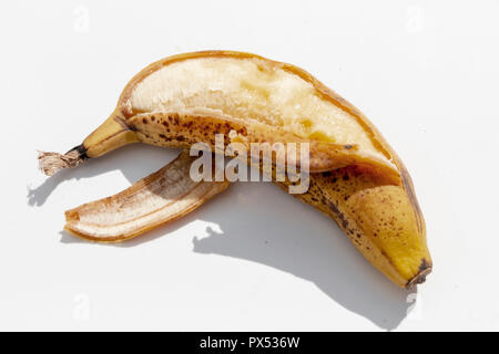 Aus der Nähe zu sehen. Eine sehr reife, gelbe Banane, die Poped hat und auf der einen Seite auf einem isolierten weißen Hintergrund geöffnet Stockfoto