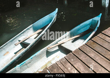 Zwei Kanus mit Holz- Ruder angedockt durch einen Steg am See Stockfoto