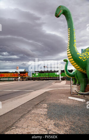 Dinosaurier im Rainbow Rock Shop mit Zug auf Atlantic & Pacific Railroad im Hintergrund. Holbrook, Arizona, USA Stockfoto