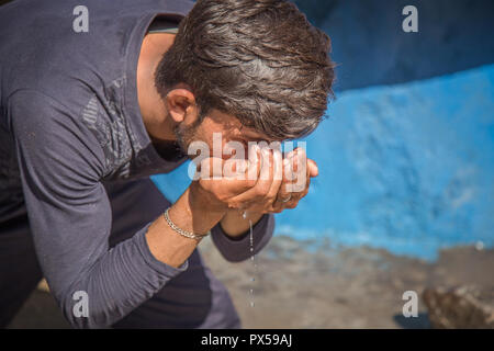 Die Hände des armen Mannes Lufthutze Trinkwasser Stockfoto