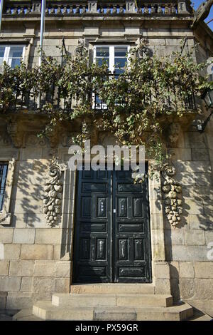 Berühmte Casa de la Parra. Haus mit steinerner Weinrebe. Balkon mit eisernem Geländer, weißen Fenstern und echtem Weinstock. Santiago de Compostela, Spanien. Stockfoto