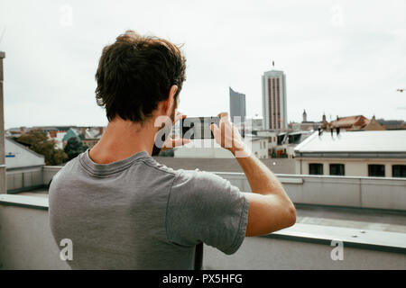 Nahaufnahme von Rückansicht der junge Mann Fotografieren einer Skyline der Stadt mit seinem Smartphone Stockfoto
