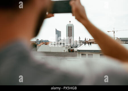 Nahaufnahme von Rückansicht der junge Mann Fotografieren einer Skyline der Stadt mit seinem Smartphone Stockfoto