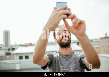 Frontalansicht des Jungen bärtigen Mann selbst fotografieren mit seinem Smartphone Stockfoto