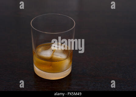 Whiskey, Bourbon, Scotch oder Rum auf den Felsen in einem eleganten Tumbler auf einem dunklen Holztisch Stockfoto