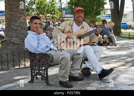 Mann spielt Gitarre und Freund im Parque Hidalgo, Tecate, Baja California, Mexiko Stockfoto