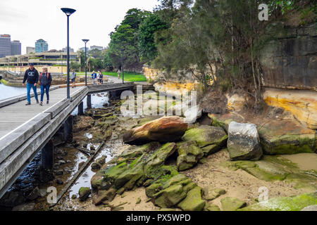 Menschen zu Fuß auf eine Promenade entlang der Woolloomooloo Bay und Königlicher botanischer Garten Sydney, NSW, Australien. Stockfoto