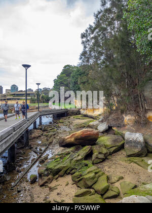 Menschen zu Fuß auf eine Promenade entlang der Woolloomooloo Bay und Königlicher botanischer Garten Sydney, NSW, Australien. Stockfoto