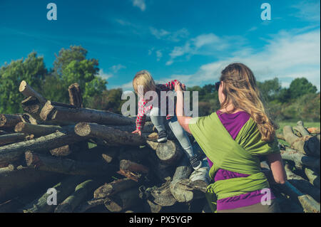 Ein kleines Kind klettern auf einige Protokolle im Wald Stockfoto