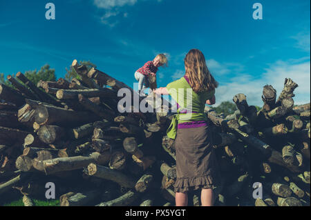 Ein kleines Kind klettern auf einige Protokolle im Wald Stockfoto