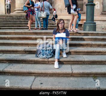 Ein Teenager Frau Studium mit einem Binder auf der Treppe einer Universität in einem Campus der Universität Stockfoto