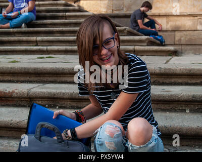 Ein Teenager Frau Studium mit einem Binder auf der Treppe einer Universität in einem Campus der Universität Stockfoto