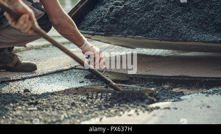 Retro Bild von zwei Arbeiter zusammen, um neue Asphalt auf beschädigten Straße mit einer Verbreitung und Vermittlung der Zement mischen und die anderen Nivellierung zu legen Stockfoto