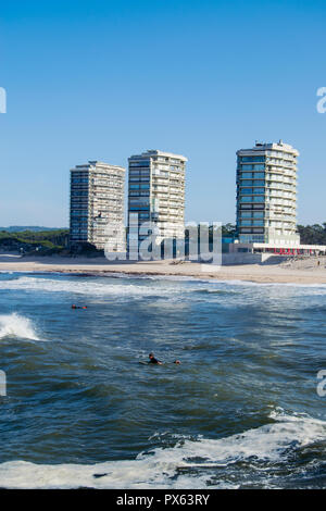 Ofir Strand in Portugal, Surfspot. Surfer auf dem Wasser mit großen Gebäuden im Hintergrund. Ozean schwellen Energie, Wassersport. Stockfoto