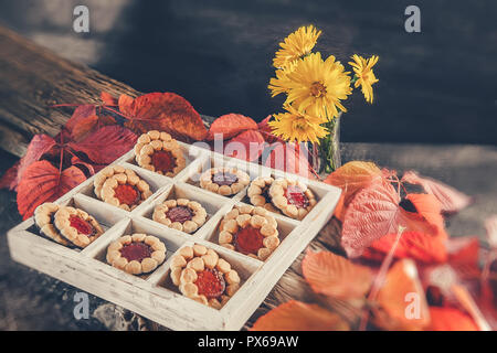 Cookies auf einem farbigen Hintergrund von Herbstlaub auf einem Holztisch. Herbstliche Stimmung. Stockfoto