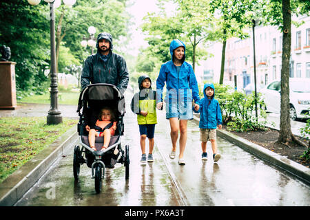 Eine Familie mit Kinder zu Fuß an regnerischen Tag mit Regenmantel Stockfoto