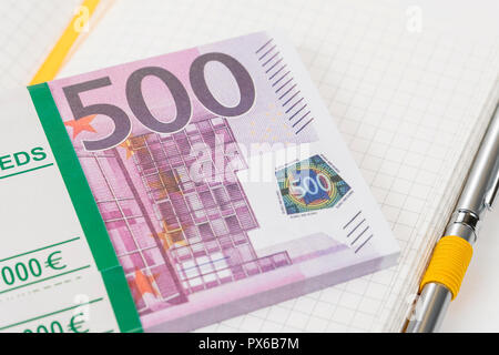 Bündel Geld in der Stückelung von 500 Euro auf einem Notebook, das Blatt in einem Käfig mit einem Stift Stockfoto