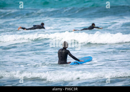 Undefinierte Surfer mit Surfbrett im Wasser des Atlantischen Ozeans, Winter auf der Insel Lanzarote, Famara Strand, berühmten Ziel für Surfer Stockfoto