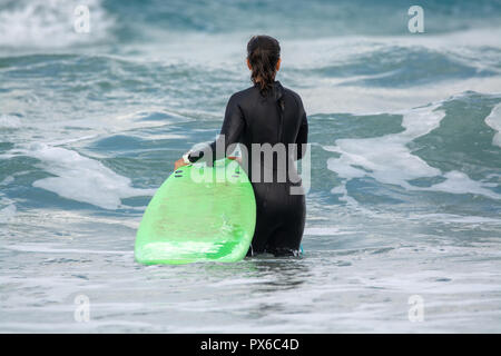 Undefinierte Surfer mit Surfbrett im Wasser des Atlantischen Ozeans, Winter auf der Insel Lanzarote, Famara Strand, berühmten Ziel für Surfer Stockfoto