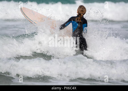 Undefinierte Surfer mit Surfbrett im Wasser des Atlantischen Ozeans, Winter auf der Insel Lanzarote, Famara Strand, berühmten Ziel für Surfer Stockfoto