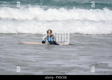 Undefinierte Surfer mit Surfbrett im Wasser des Atlantischen Ozeans, Winter auf der Insel Lanzarote, Famara Strand, berühmten Ziel für Surfer Stockfoto