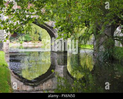 Steinerne Brücke in den Graben in Eltham Palace Gärten wider Stockfoto