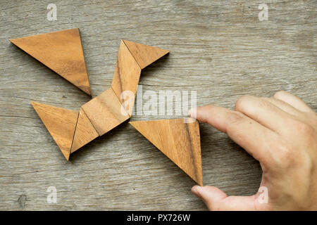 Mann halten Dreieck, Tangram-Puzzle in Vogel-Form zu erfüllen (Konzept für die Freiheit, frei leben oder entdecken Sie neue Welt) Stockfoto