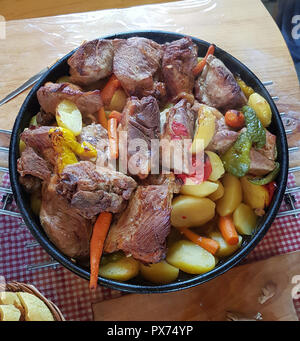 Traditionelle kroatische Gerichte Peka, Fleisch und Gemüse in Eisen Abdeckung unter warmes Licht. Stockfoto