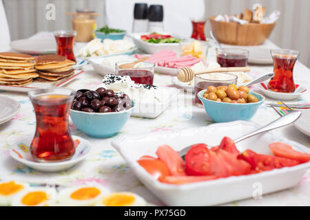 Türkisches Frühstück mit simit (Bagel) Pfannkuchen, Käse, Cherry Tomaten, Gurken, und Tee auf einem Tisch, Nahaufnahme, selektiver Fokus Stockfoto