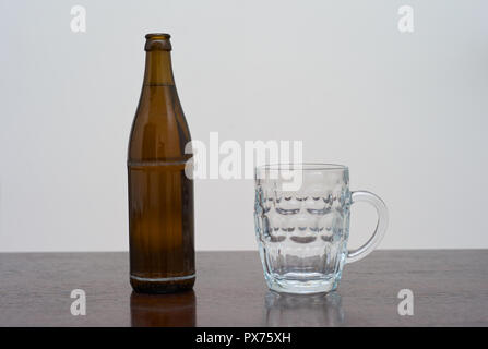 Leeres, dimptes Pint-Glas und eine Flasche Bier auf Ein brauner Holztisch Stockfoto