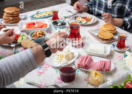 Türkisches Frühstück mit simit (Bagel) Pfannkuchen, Käse, Cherry Tomaten, Gurken, und Tee auf einem Tisch, Nahaufnahme, selektiver Fokus Stockfoto
