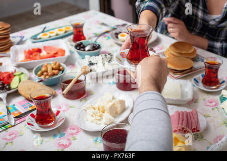 Türkisches Frühstück mit simit (Bagel) Pfannkuchen, Käse, Cherry Tomaten, Gurken, und Tee auf einem Tisch, Nahaufnahme, selektiver Fokus Stockfoto