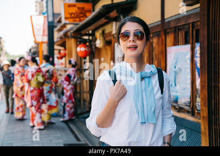 Freudige touristische Wandern in den japanischen Straße mit jungen Mädchen, die Kimono im Hintergrund. berühmten Kyoto Tourist Spots für Backpacker. Junge trav Stockfoto