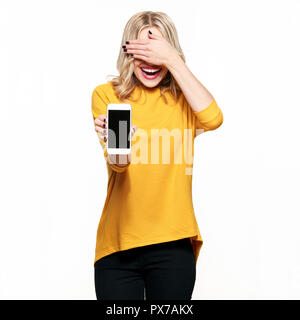 Wunderschöne lachende Frau, leeren Bildschirm Mobiltelefon über weißen Hintergrund, die ihre Augen mit der Hand. Sehr aufgeregt, jubelnde Emotion. Stockfoto
