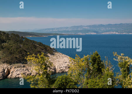 Blaue Wasser der Adria. Bäume auf beide Teile der Bucht. Die Berge im Hintergrund. Trübe frühlingshimmel. Blick von der Stadt Crikvenica, Insel Krk, Kroatien Stockfoto