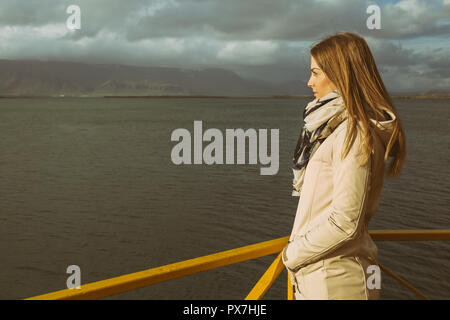 Frau am Hafen in Reykjavik und Blick auf das Meer. Image enthält wenig Lärm wegen der hohen ISO auf Kamera eingestellt und es getönt. Stockfoto