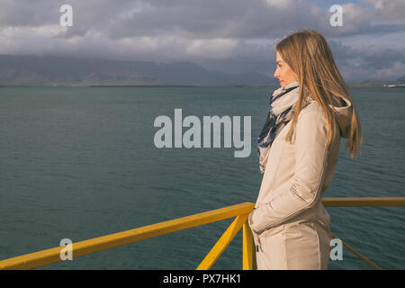 Schöne Frau am Hafen in Reykjavik und bietet Blick auf das Meer. Image enthält wenig Lärm wegen der hohen ISO auf Kamera eingestellt und es Stockfoto